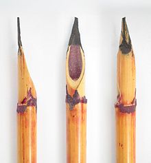 Tres cálamos de caña tallados, con la punta manchada de tinta roja y violeta