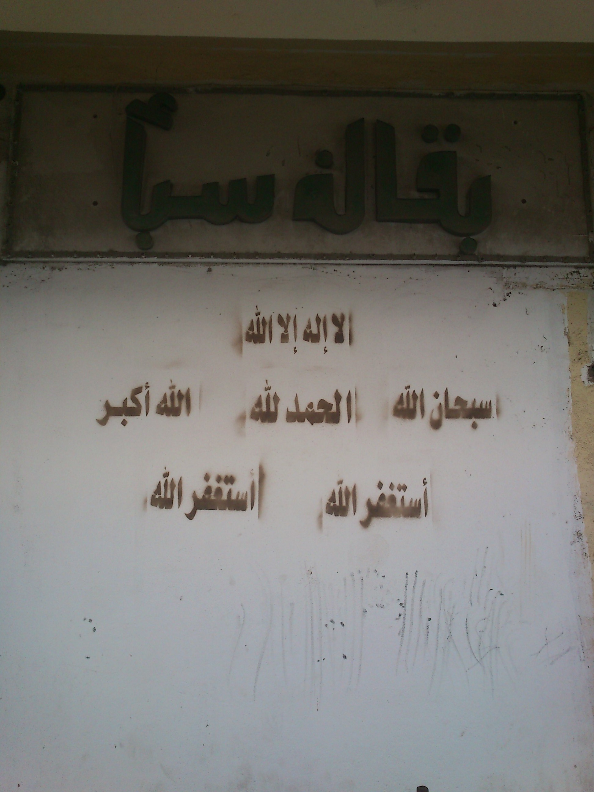 Pared de una tienda con fórmulas pintadas con plantilla: سبحان الله, الحمد لله, الله أكبر y أستغفر الله